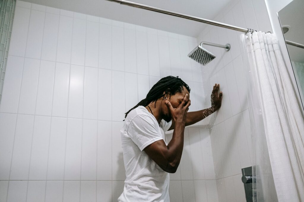 Man showering in a tiled bathroom