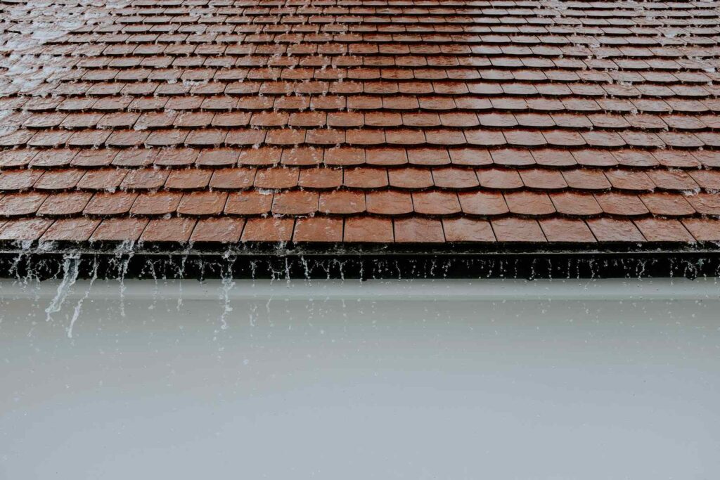 Rainwater overflowing from roof shingles into gutter