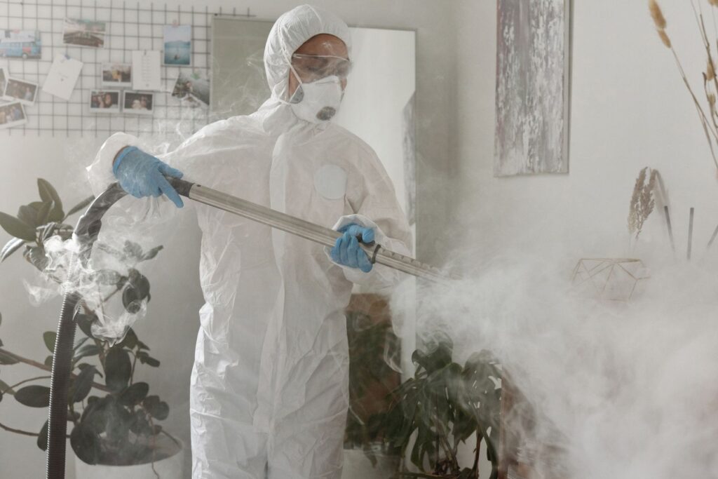 Worker in protective gear treating an indoor space