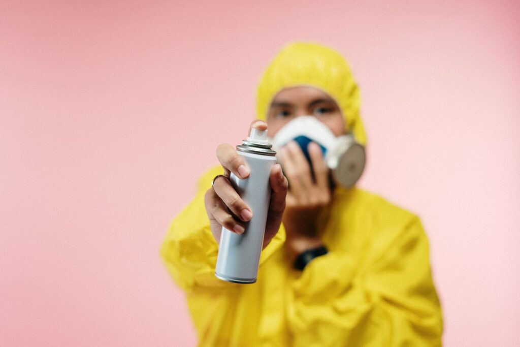 A man in protective gear holding an aerosol can