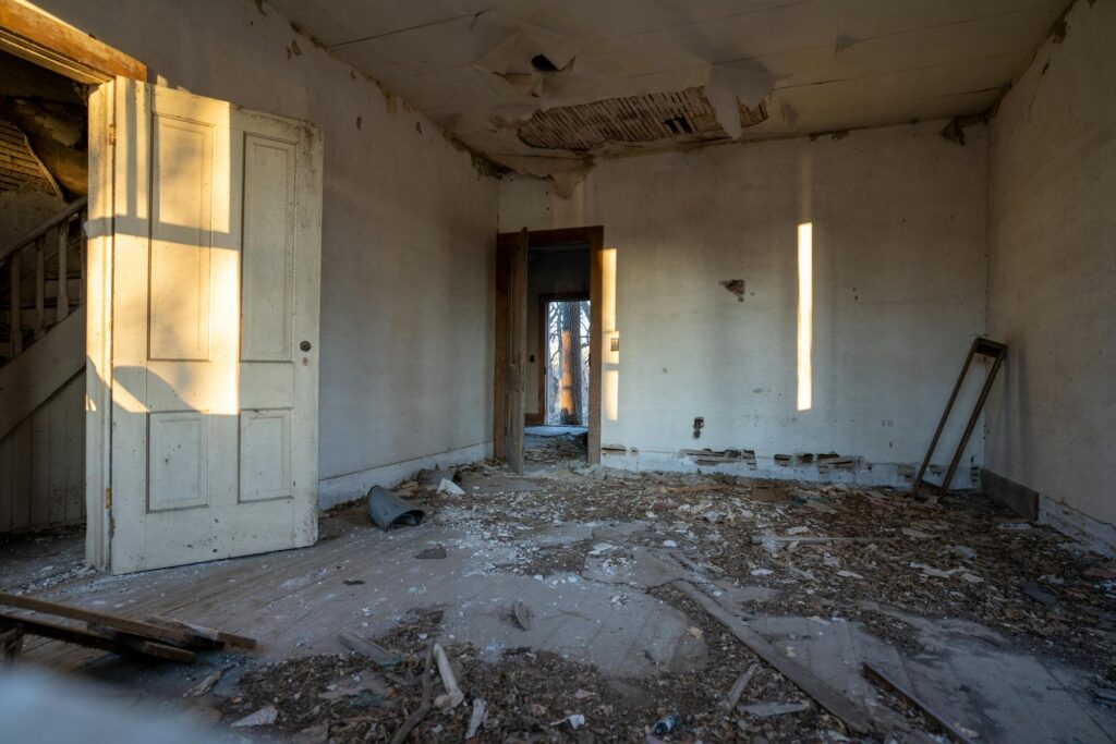 Abandoned room with peeling paint and debris on floor