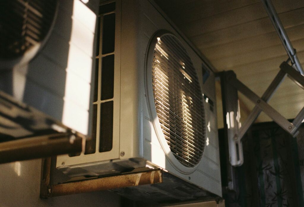 Outdoor HVAC condenser unit mounted on exterior wall in sunlight