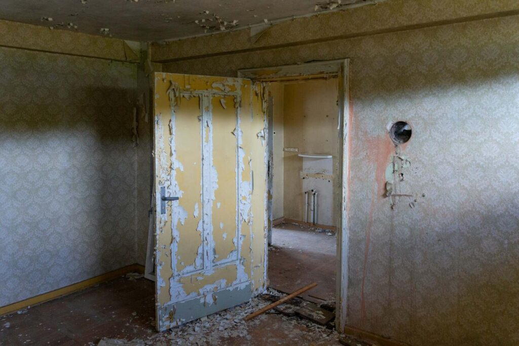 Peeling paint and damaged walls in older home interior