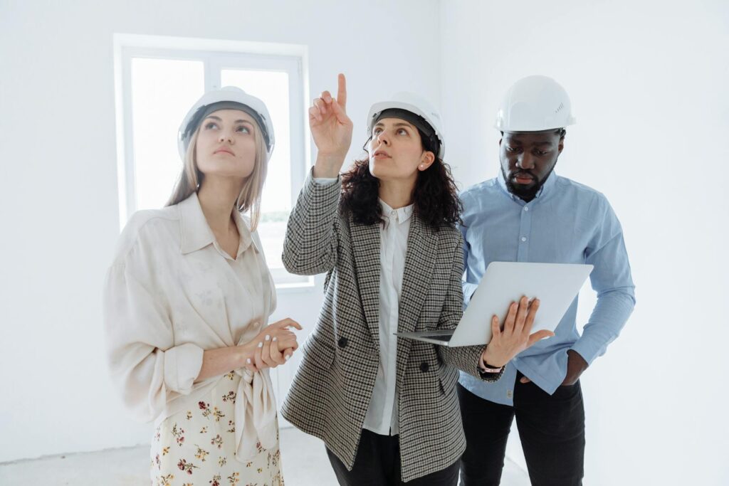 Inspectors in hard hats examining interior wall and ceiling