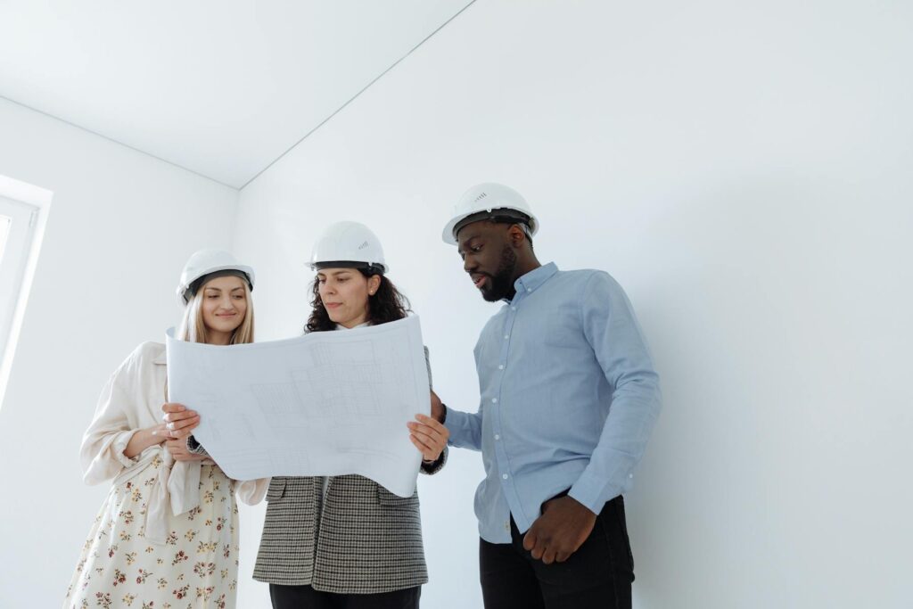 Inspectors in hard hats reviewing blueprints inside a property