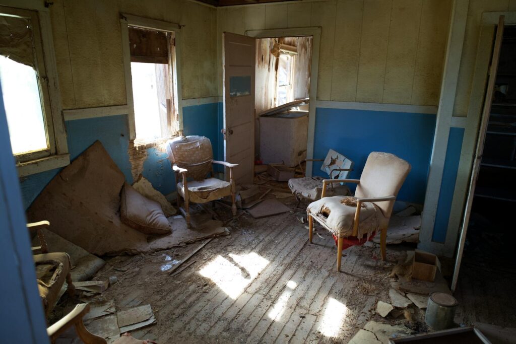 Dusty abandoned room with torn chairs and sunlight on the floor