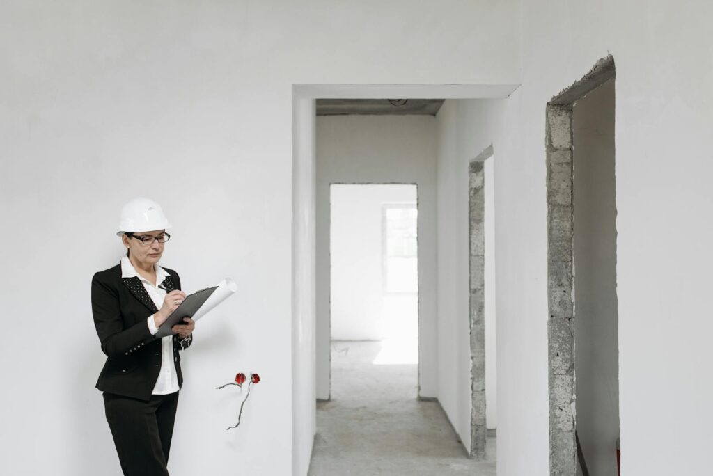 Inspector in a hard hat taking notes inside an unfinished home