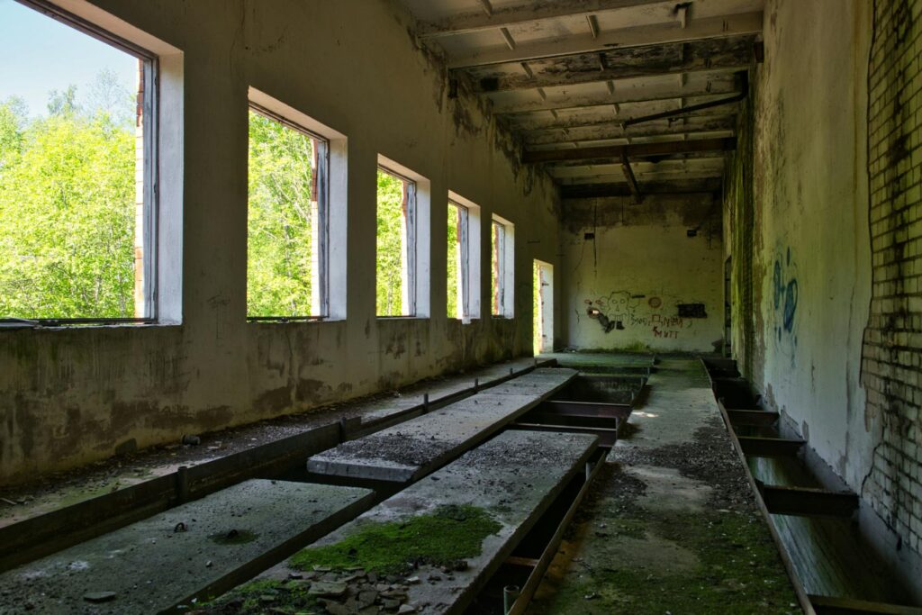 Abandoned industrial room with broken concrete channels and sunlight through windows