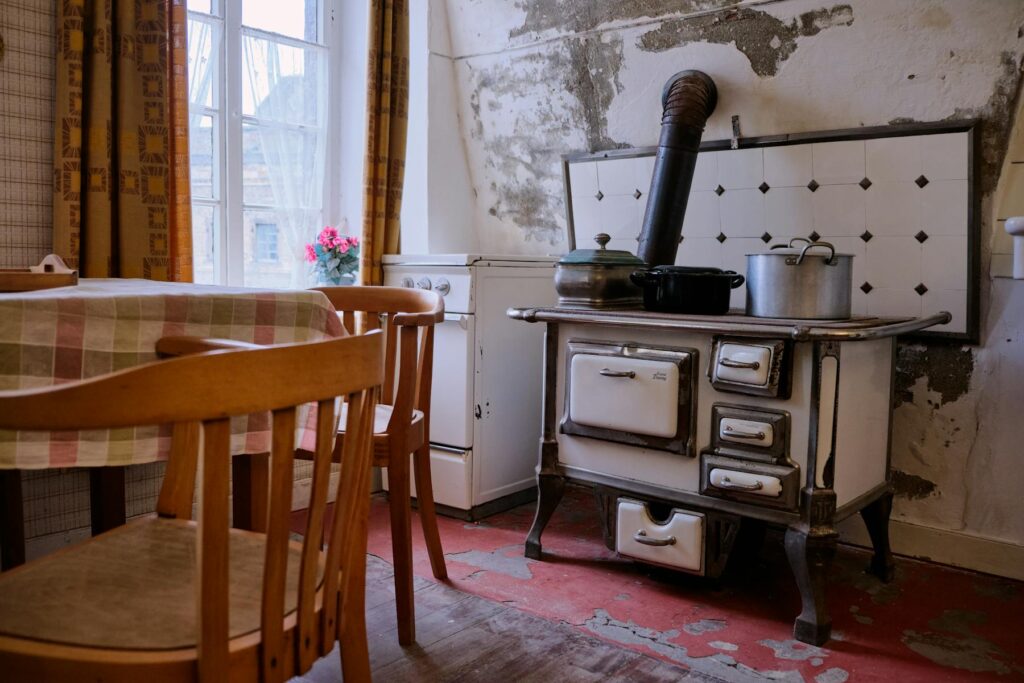 Old kitchen with peeling walls and stove