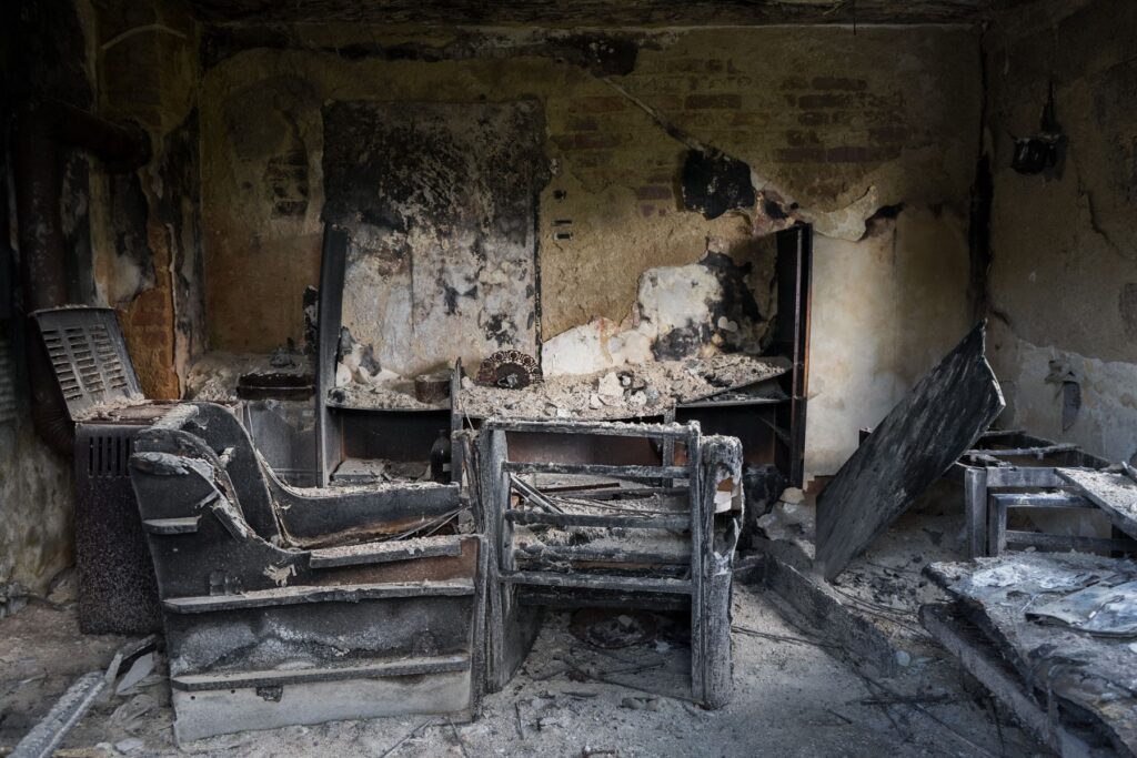 Fire-damaged room with charred furniture and heavy soot