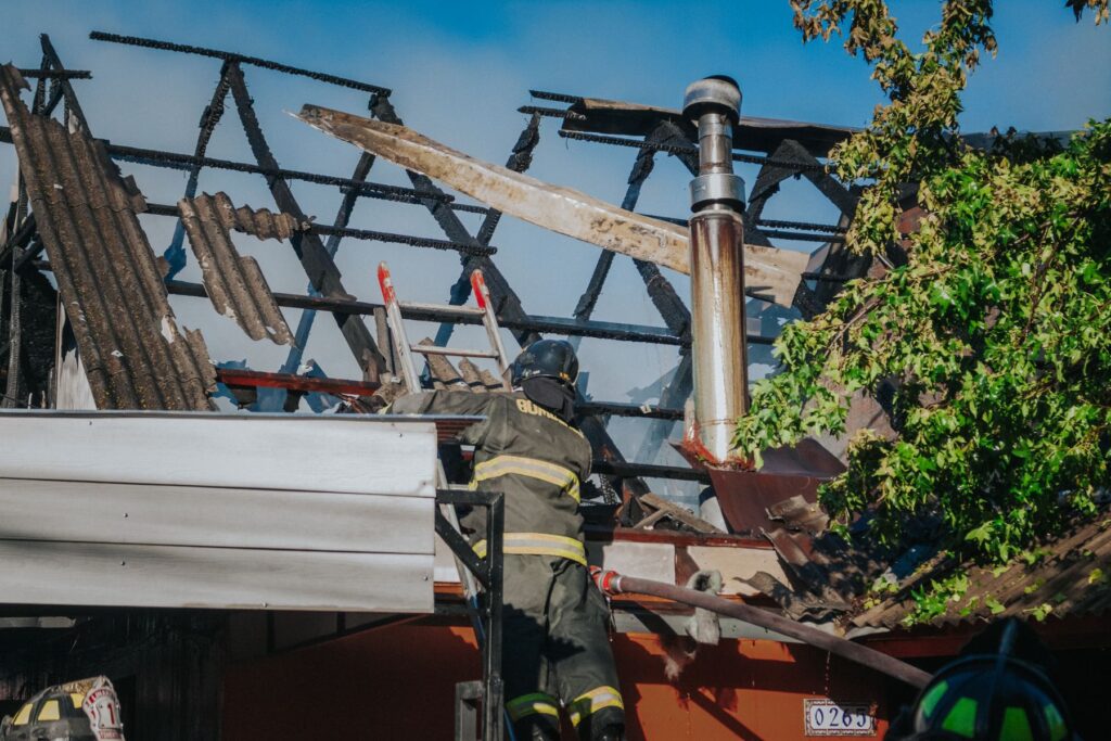 Firefighter inspecting severe structural fire damage