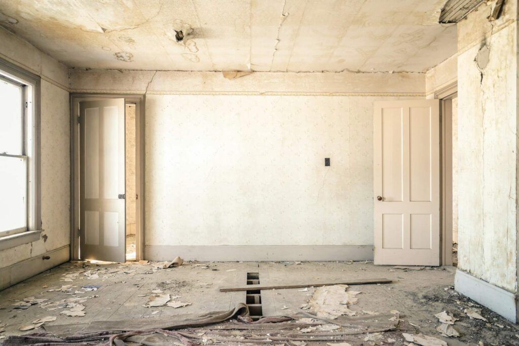 Damaged room with peeling ceiling and debris