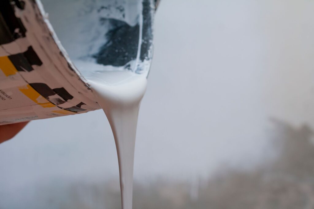 Fresh white paint being poured from a paint can