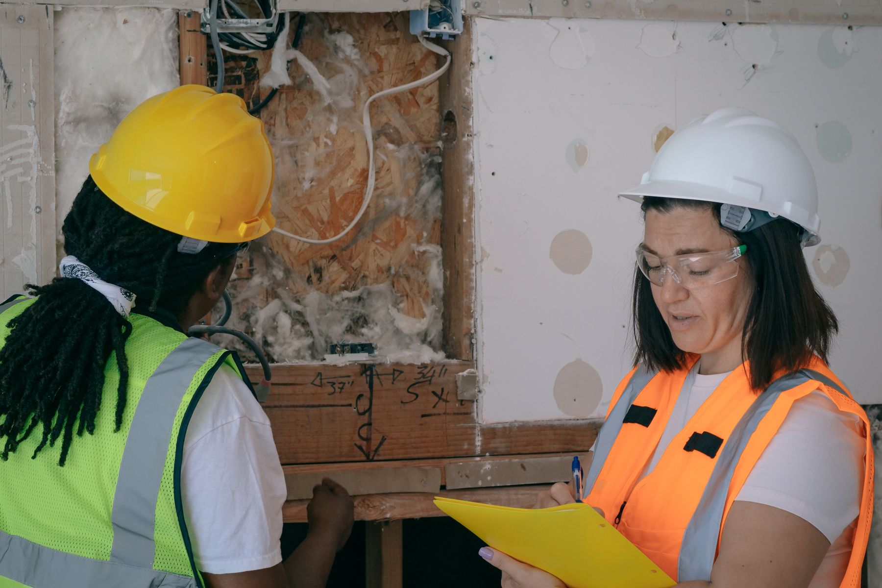 Building inspectors documenting exposed wall framing and insulation during an inspection
