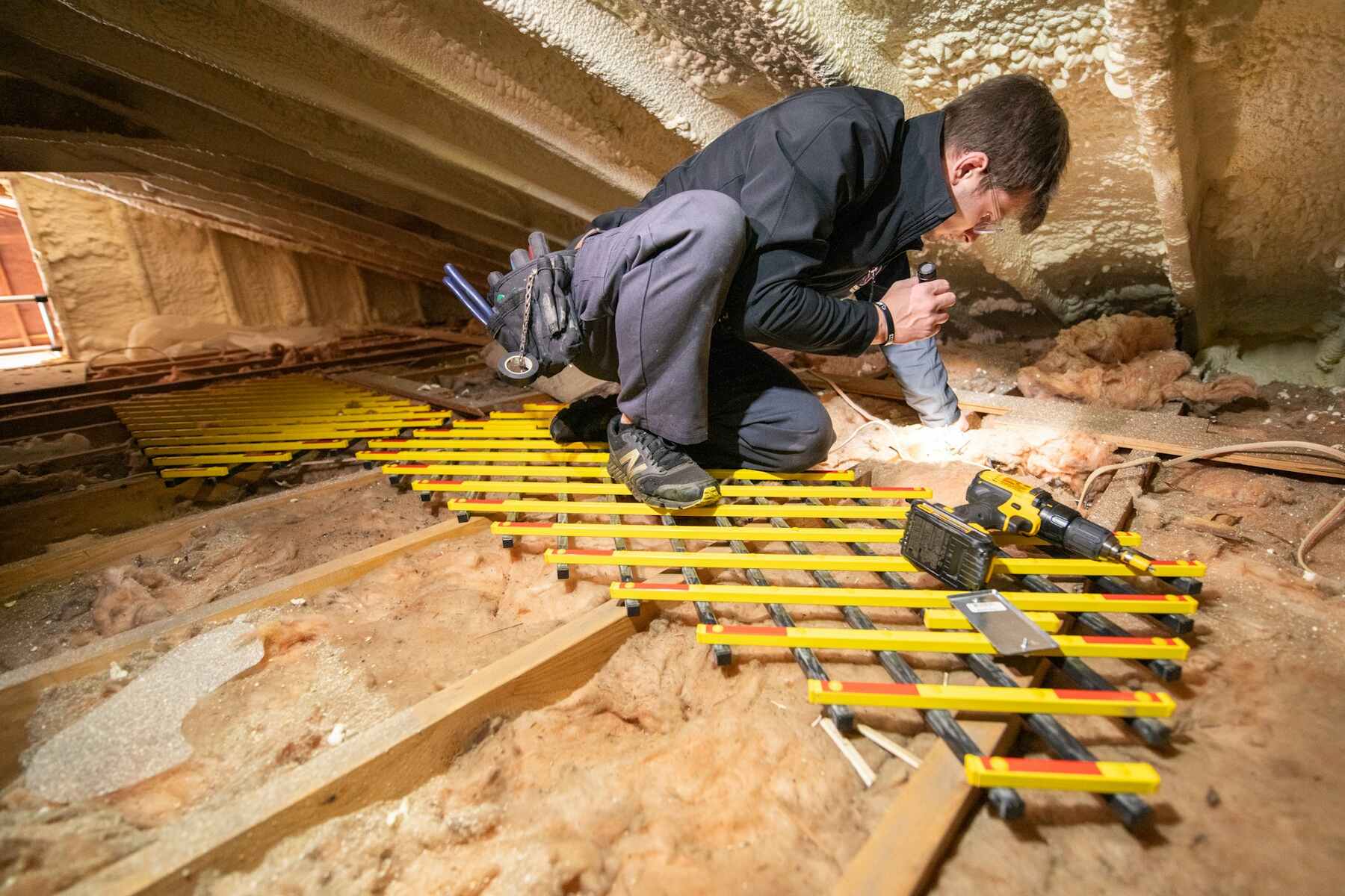 Home inspector examining an insulated crawl space with a flashlight