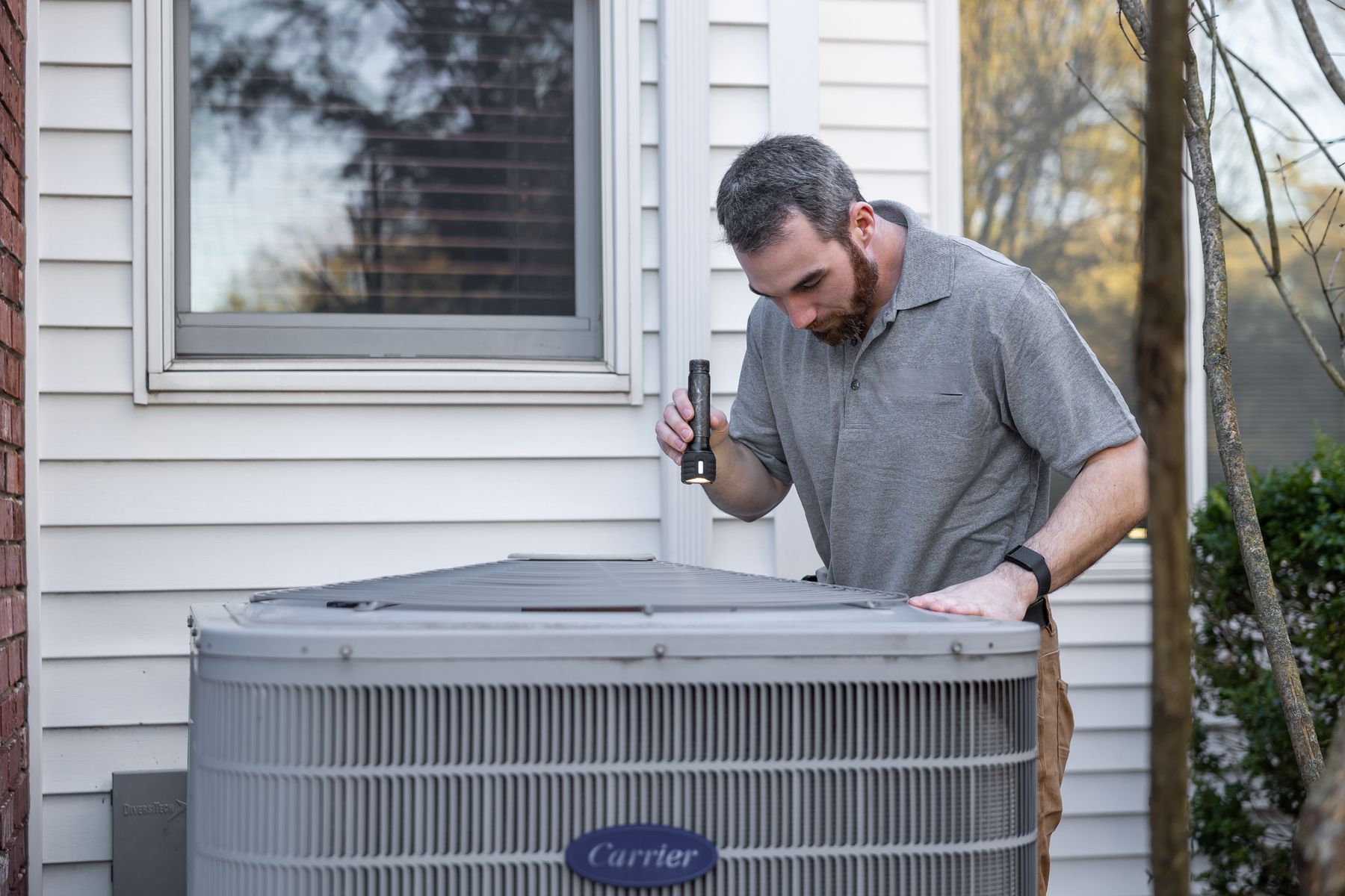 Technician inspecting an outdoor HVAC unit for air quality concerns
