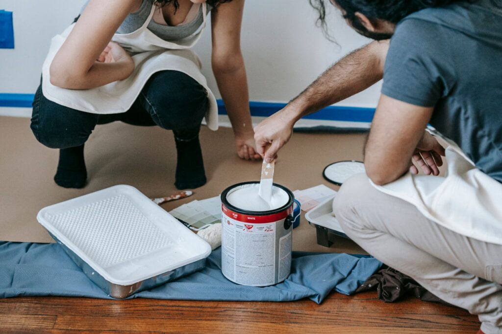Two people preparing white paint for an indoor painting project