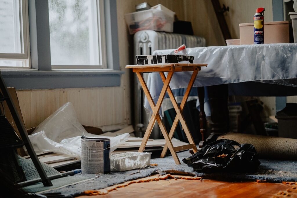 Interior room undergoing renovation with paint supplies and protective coverings
