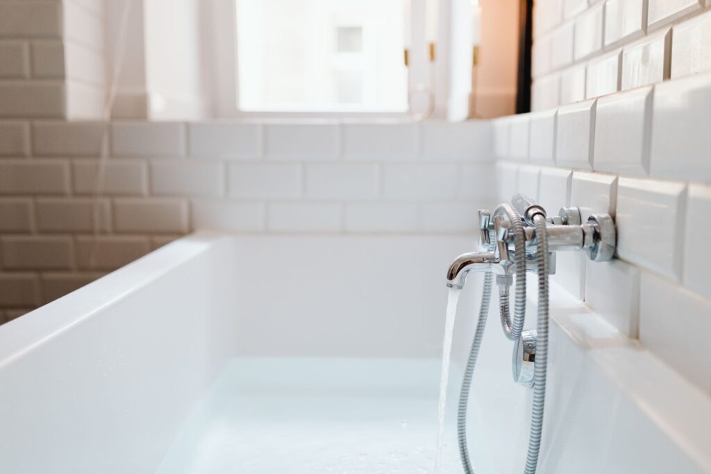 Bathtub faucet running water in a tiled bathroom