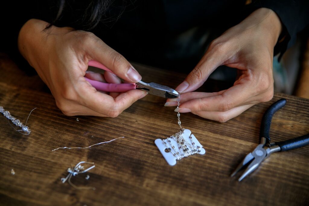 Hands using pliers to work on a jewelry chain.